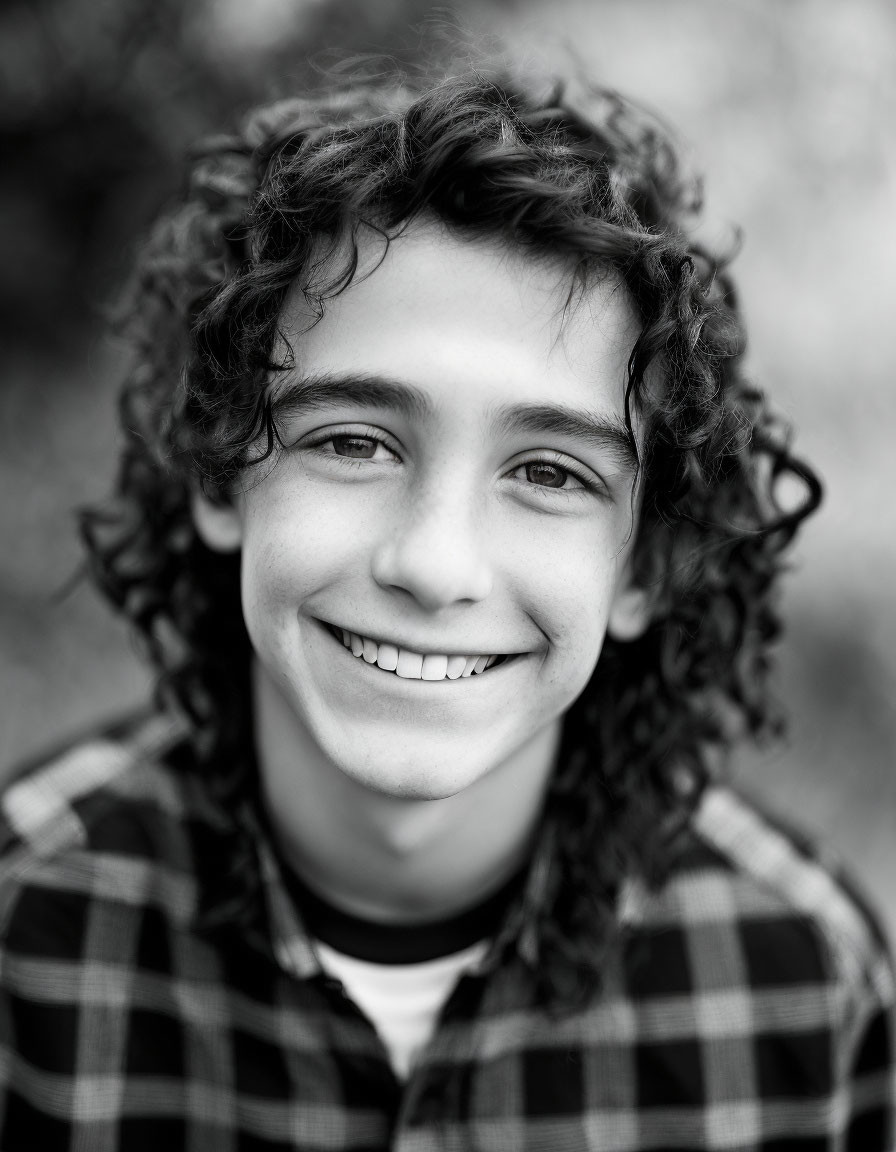 Smiling young person with curly hair in checkered shirt portrait