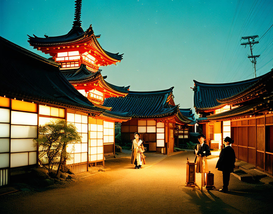 Three people talking near illuminated Japanese pagoda at dusk