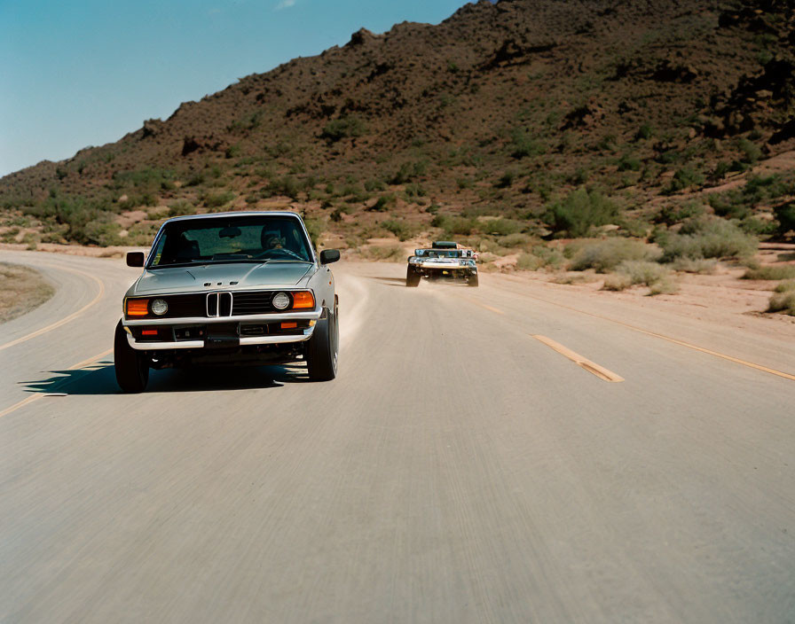 Vintage BMW car driving in desert with clear blue sky