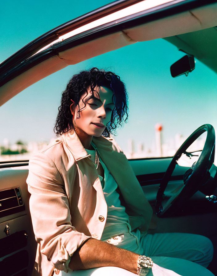 Curly-Haired Person in Light Jacket Driving Convertible Under Clear Blue Sky