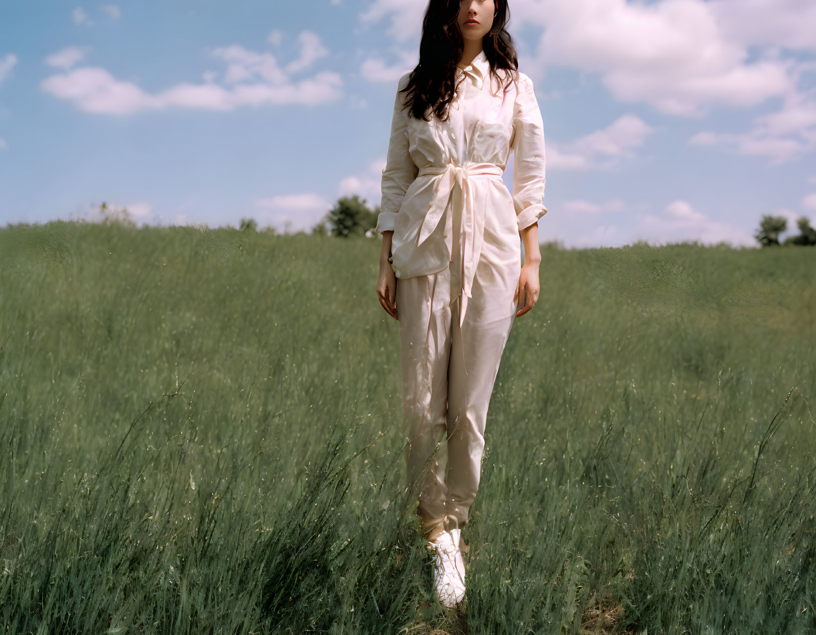 Person in White Outfit Standing in Green Field Under Blue Sky