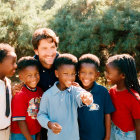 Man with six joyful children outdoors smiling.