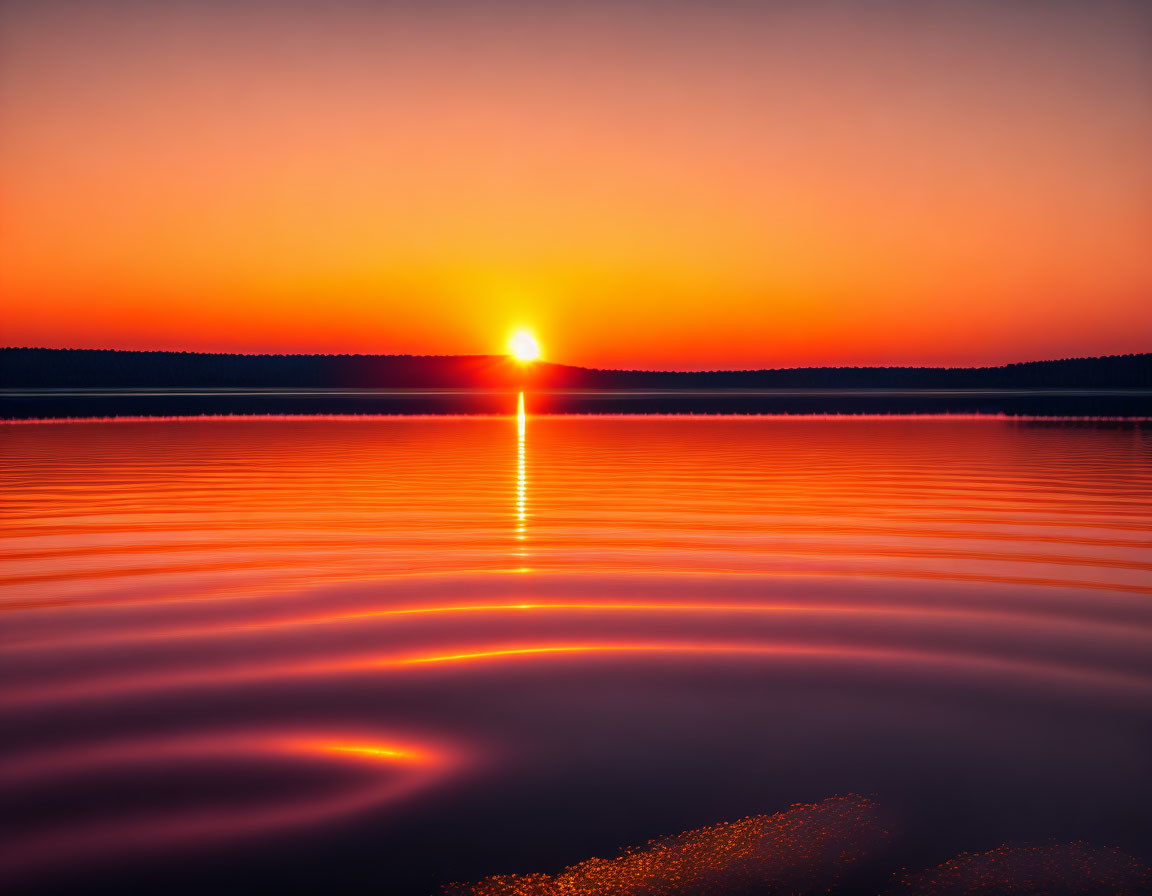 Tranquil sunset scene with vibrant orange glow over calm water