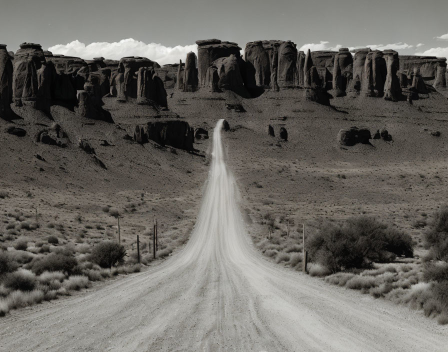 Monochrome photograph of dirt road and rock formations in desert