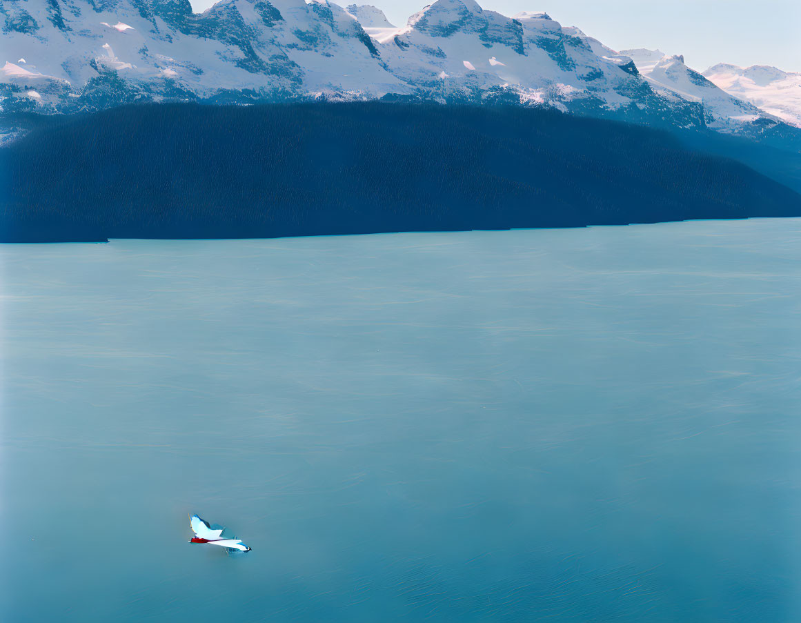 Scenic image of small boat on turquoise waters with snow-capped mountains