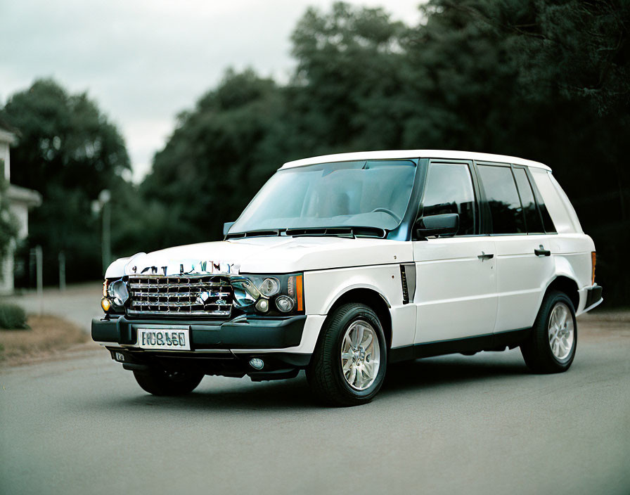 White Range Rover parked on asphalt road with "CABINNY" license plate