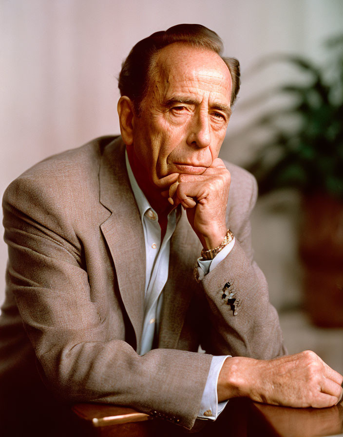 Elderly man in suit with pensive look resting chin on hand