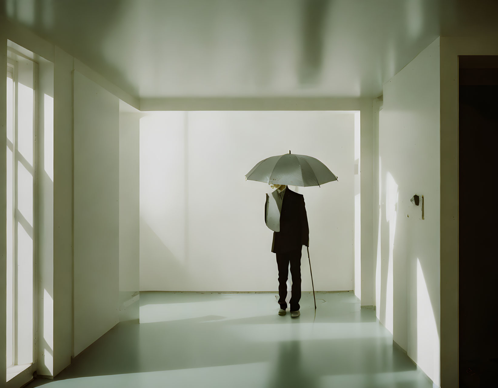 Silhouette of Person with Umbrella Against Brightly Lit Wall