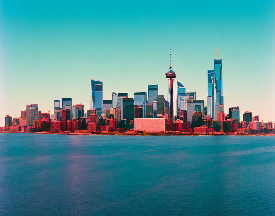 City skyline with skyscrapers and tower near calm blue water.