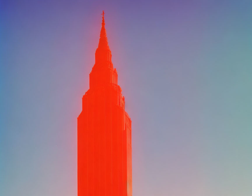 Skyscraper illuminated in red against blue sky