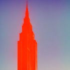 Skyscraper illuminated in red against blue sky