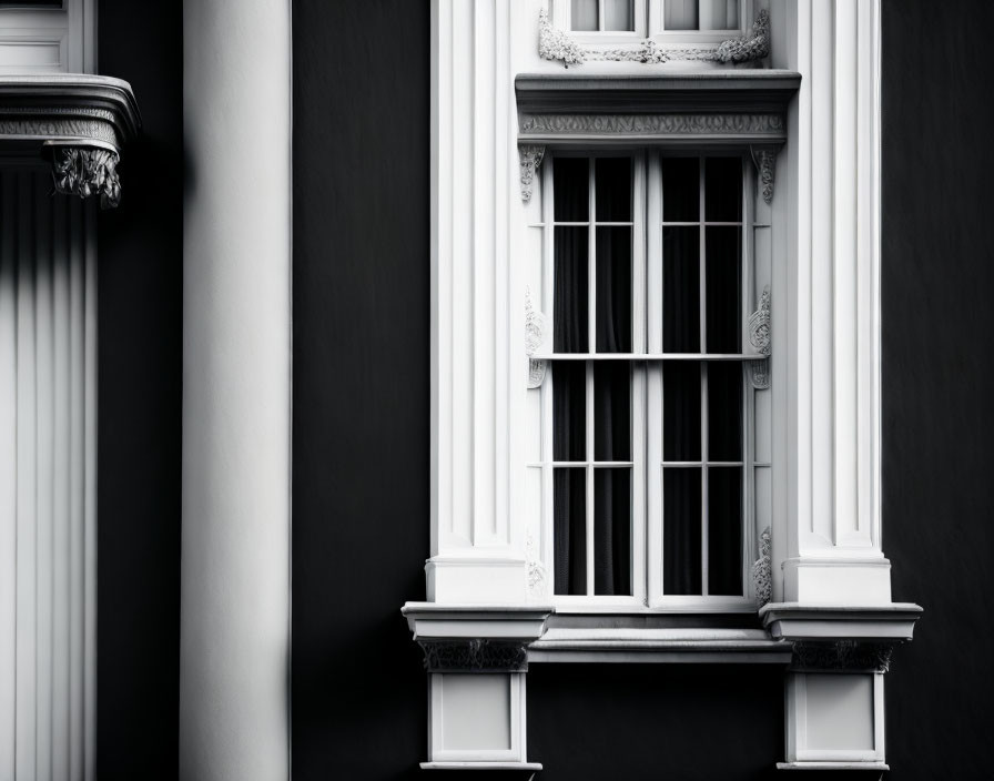 Monochrome classical building facade with ornate columns and barred window