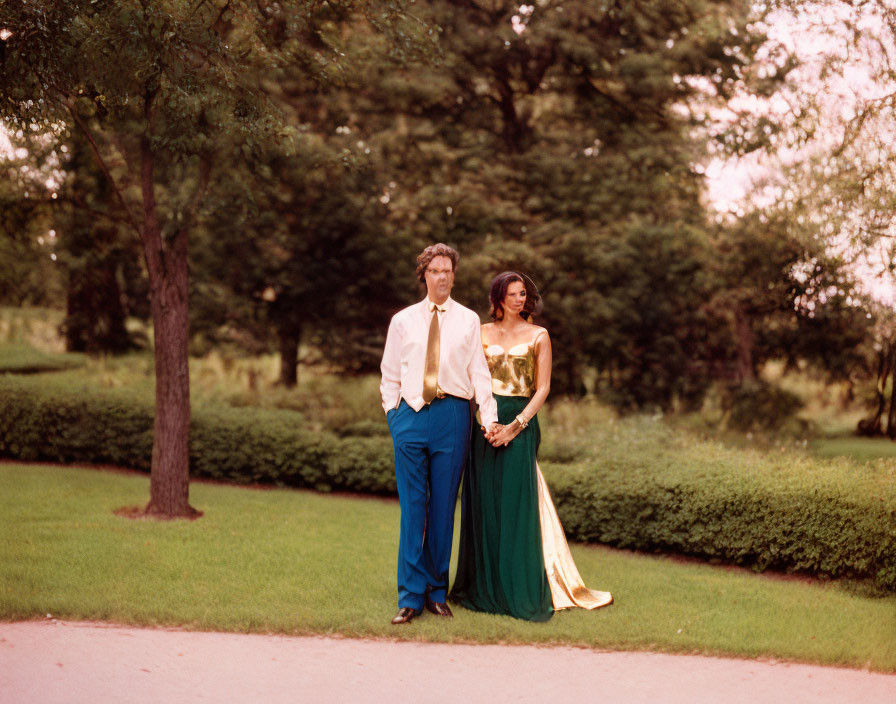 Masculine and feminine individuals in retro formal attire on grassy path