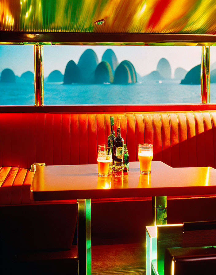 Red Upholstered Booth Overlooking Serene Sea View with Beer and Liquor Bottles