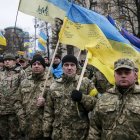 Vintage soldiers in blue and yellow uniforms with large flag in forest