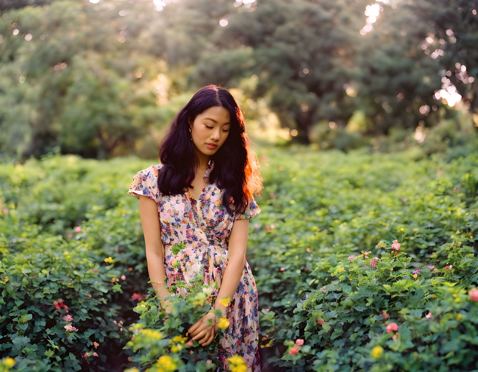 Woman in Floral Dress Standing Among Green Foliage with Sunlight Filtering Through Trees