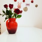 Red Vase with Roses, Decorative Plates, and "AMOR" Sign on White Table