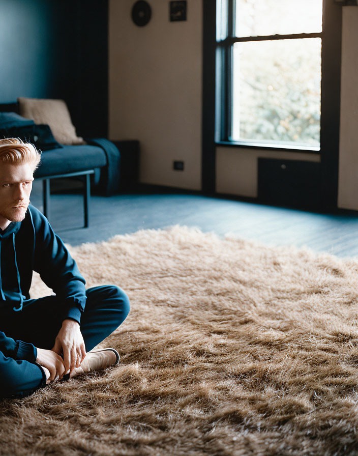 Man sitting cross-legged on shaggy rug in modern room