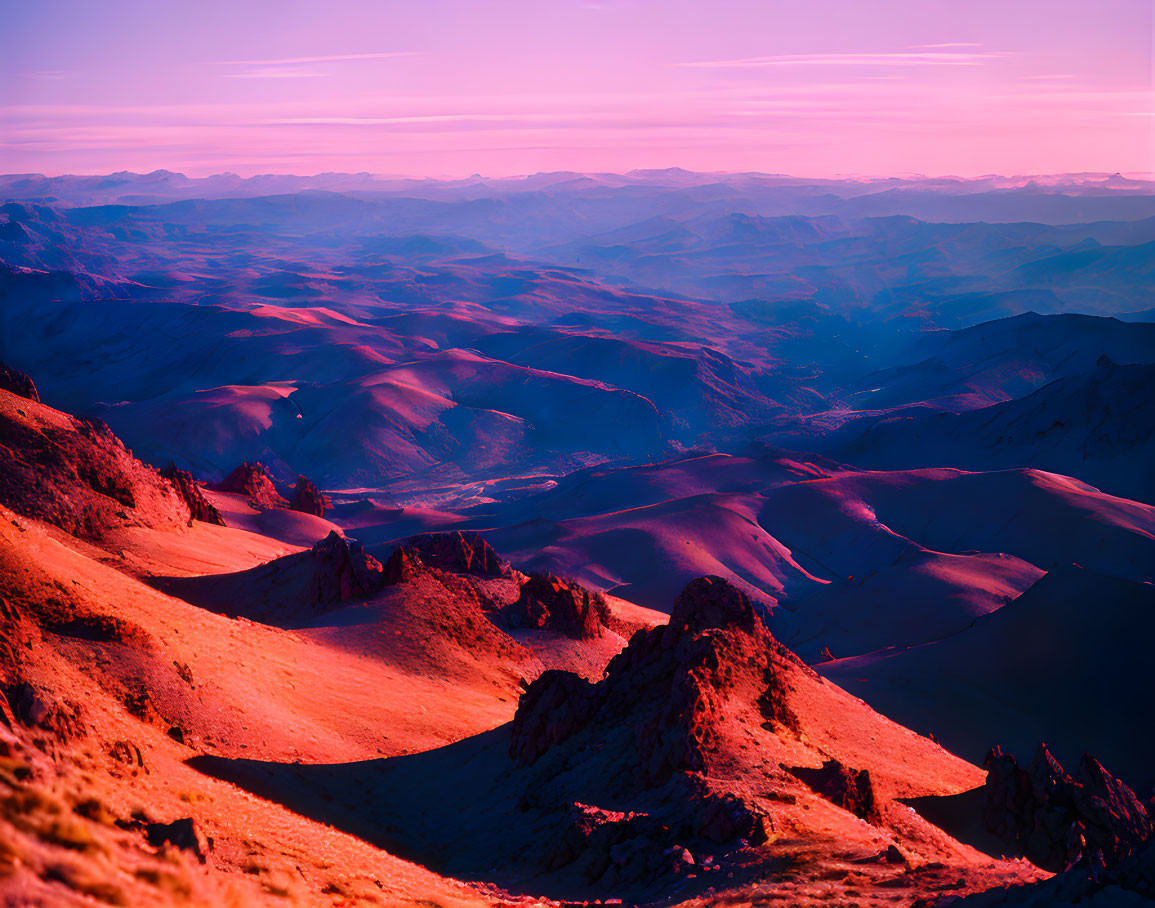 Colorful sunrise illuminates rocky landscape with pink, purple, and orange hues