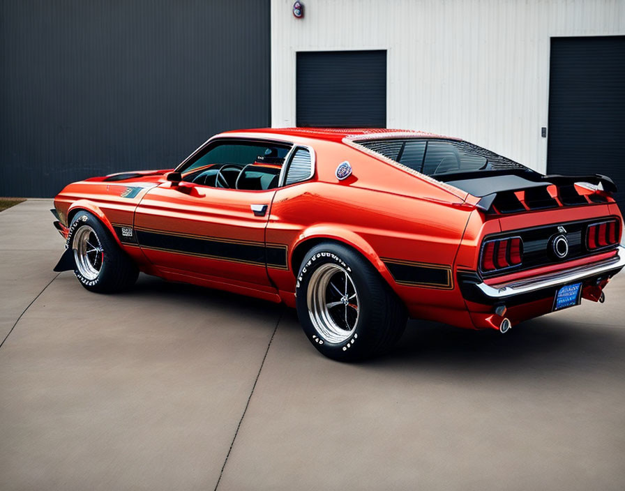 Vintage red Mustang Mach 1 with black stripes parked on concrete.