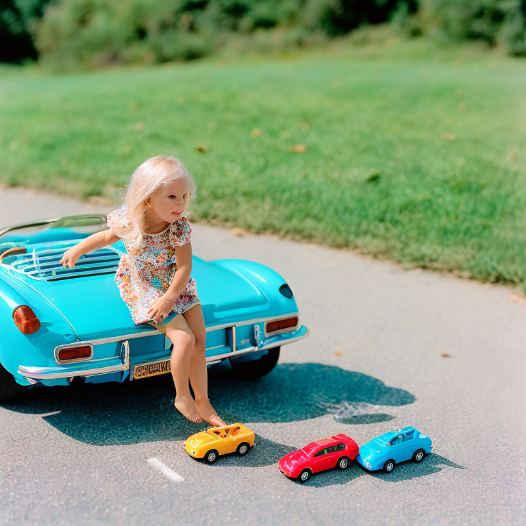 Young girl playing with toy cars on sunny day with green background