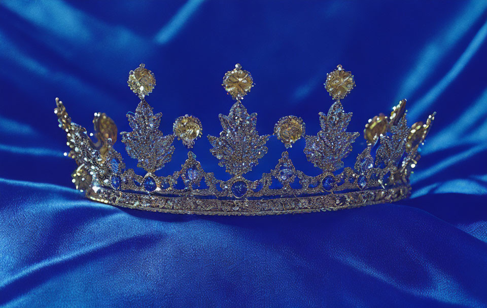 Intricate Golden Tiara with Gemstones on Blue Satin Fabric