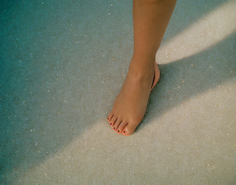 Red Nail Polish on Bare Foot Stepping on Sandy Beach