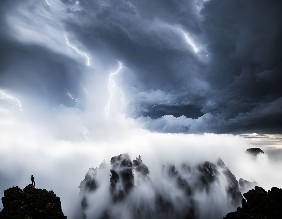 Solitary figure on mountain peak gazes at lightning bolts in dramatic sky