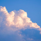 Fantastical landscape with castle on cliff amid towering peaks & sunset-hued clouds