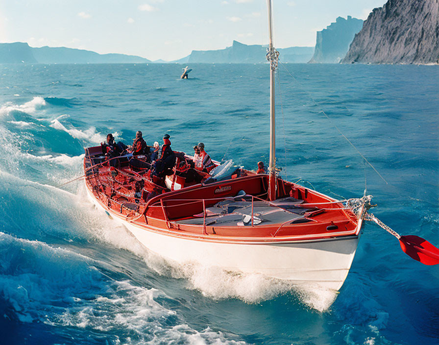 Red sailboat with crew sailing on blue waves near mountainous coastline