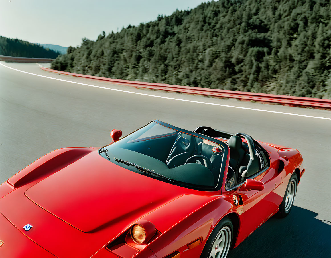 Red Convertible Sports Car Driving on Road with Trees and Blue Skies