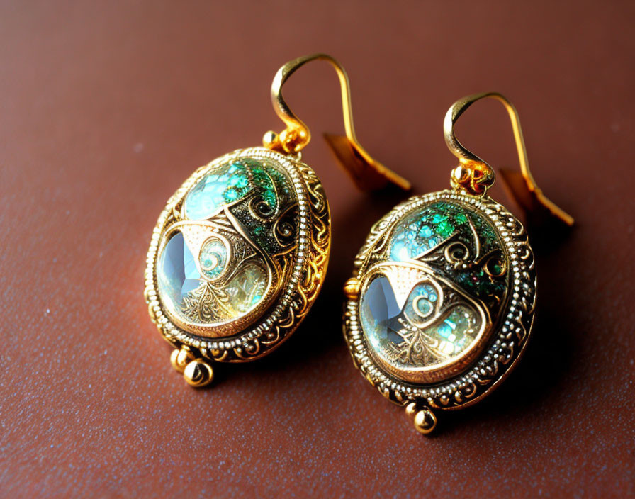 Gold Filigree Earrings with Green Enamel & Blue Gemstones on Brown Surface