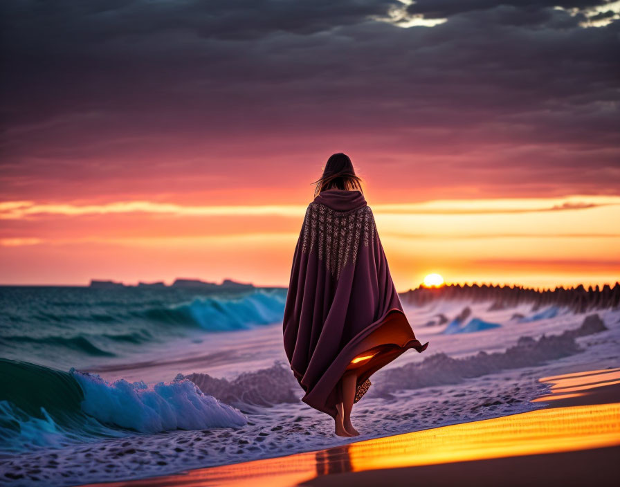 Person walking on beach at vibrant sunset with blanket and crashing waves