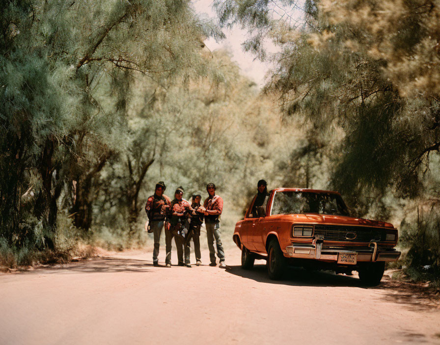 Group of People Standing by Red Vintage Car on Dusty Road