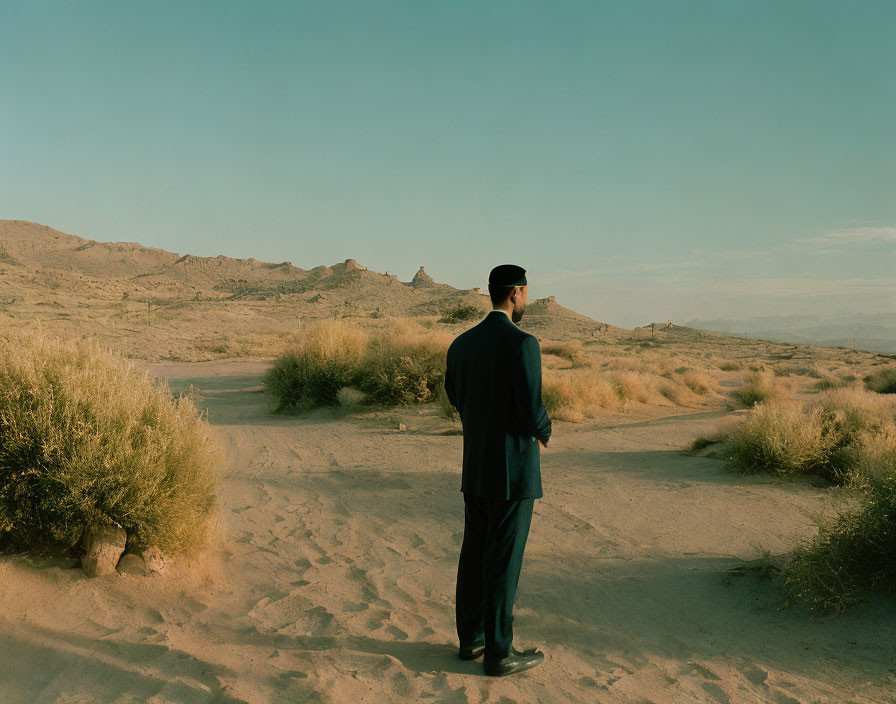 Uniformed man in desert with mountains under clear sky