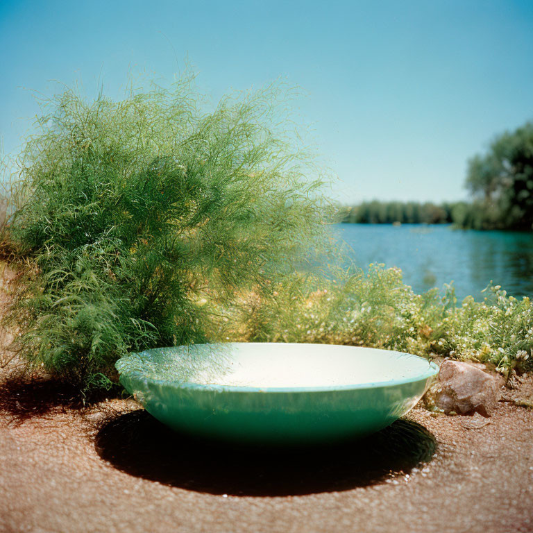 Light Green Boat Overturned on Sandy Shore with River and Greenery