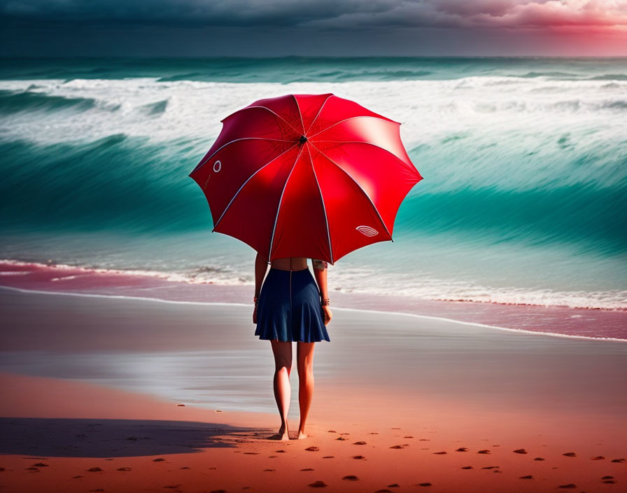 Person holding red umbrella on beach with turquoise sea and dramatic sky