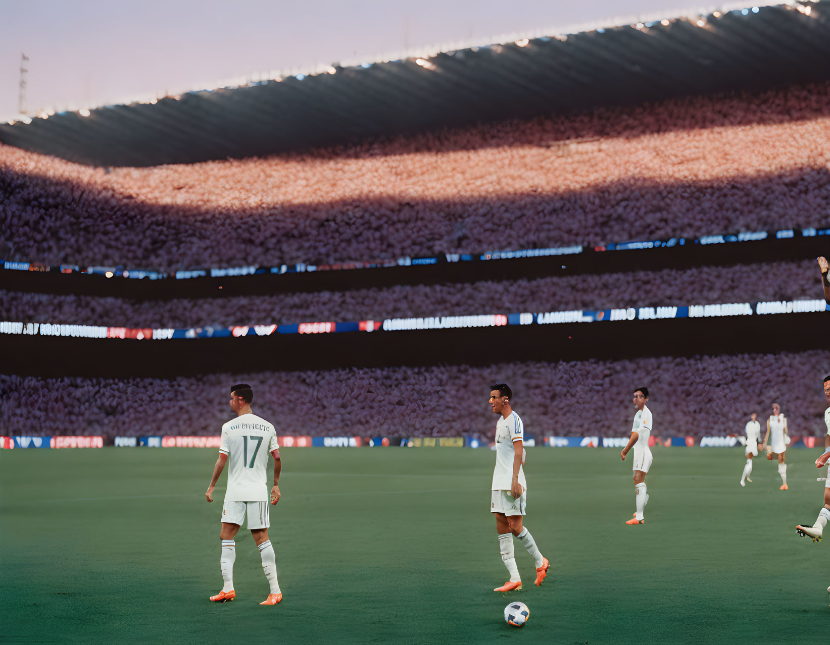 Soccer players on pitch with full stadium at dusk