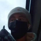 Person in Black Baseball Cap and Face Mask by Raindrop Window