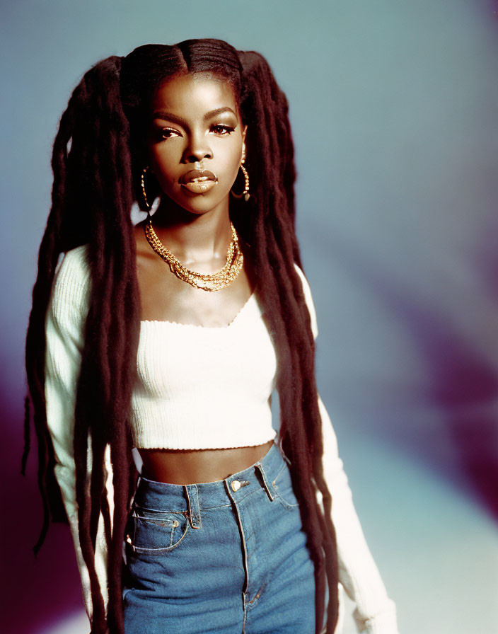 Woman with Long Dreadlocks in White Crop Top & High-Waisted Jeans on Blue Background