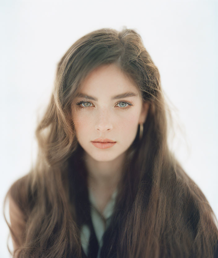 Woman with Long Brown Hair and Blue Eyes Against Bright Background