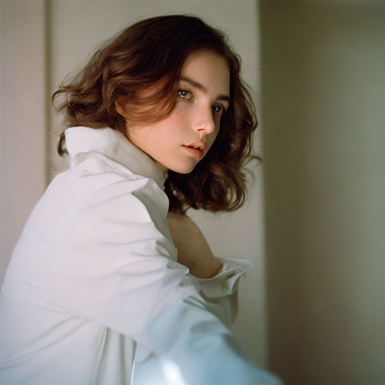 Woman with Wavy Brown Hair in White Shirt Looking Over Shoulder