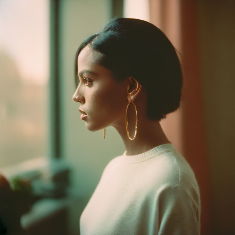 Woman with Bob Haircut Looking Out Window in Sunlight