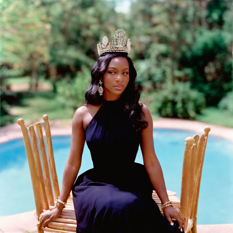 Regal woman in crown and dark dress on wooden throne chair by pool