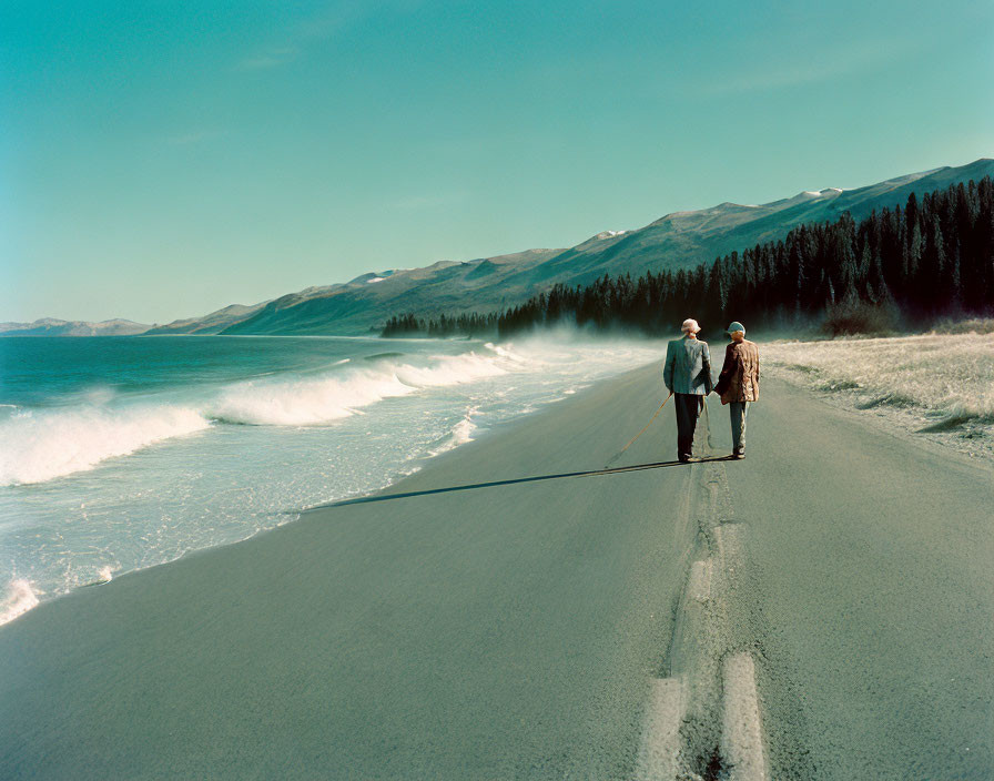 Elderly couple walking on deserted beach with mountain backdrop