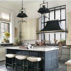 Spacious kitchen with white cabinetry, blue island, gold fixtures, and large windows.