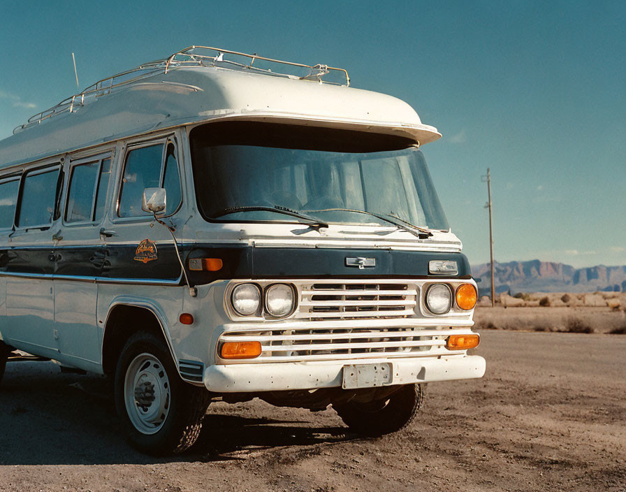 Vintage Bus Parked on Roadside with Blue Skies and Mountains