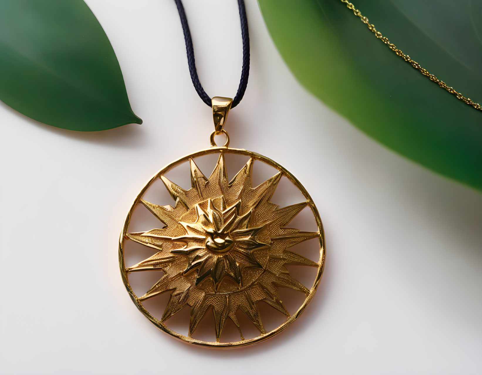 Golden Sun-Shaped Pendant with Green Leaf on Creamy Background