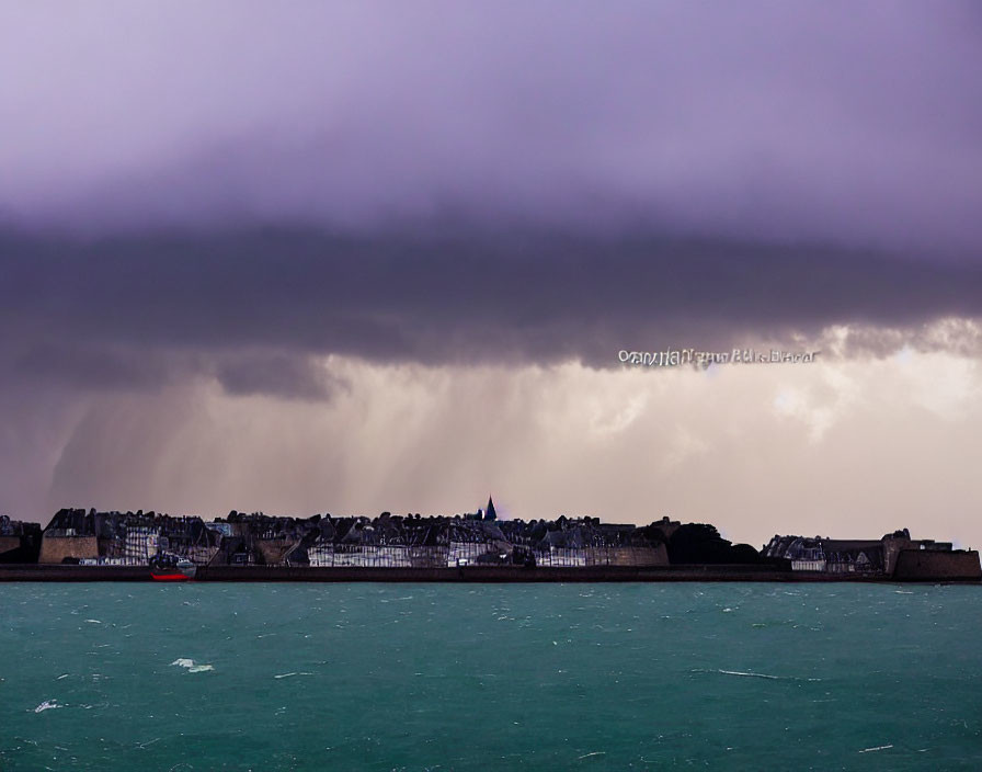 Coastal town under stormy sky with red boat on teal sea