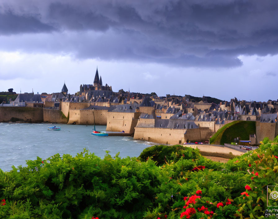 Medieval walled city by the sea with boats, flowers, and cloudy sky